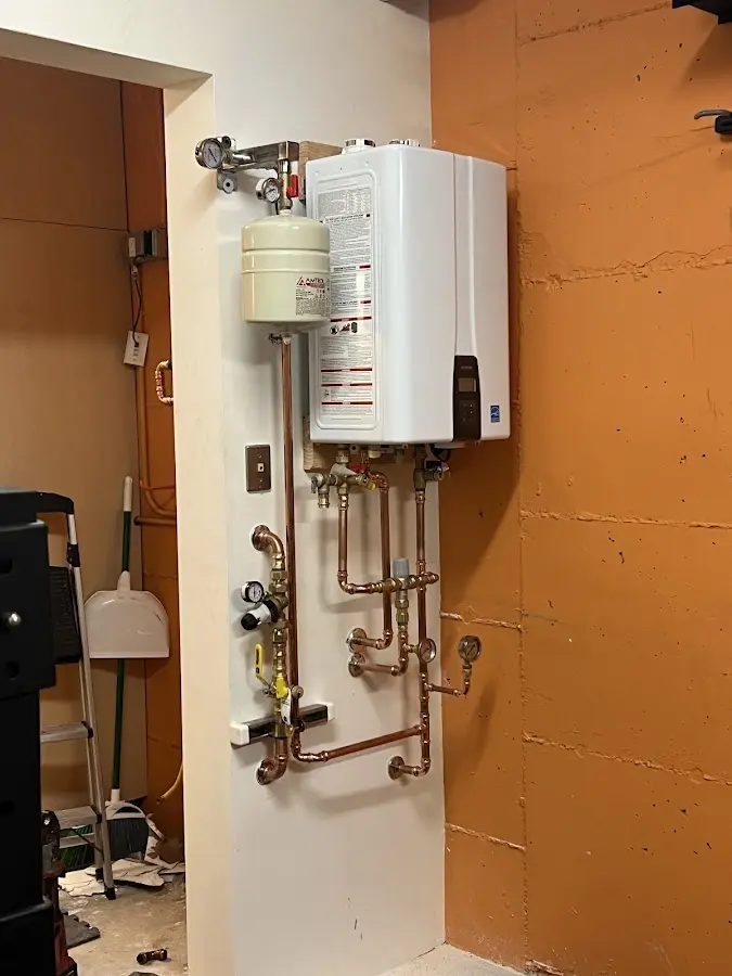 Plumbing technician inspecting water heater connections in Broadalbin
